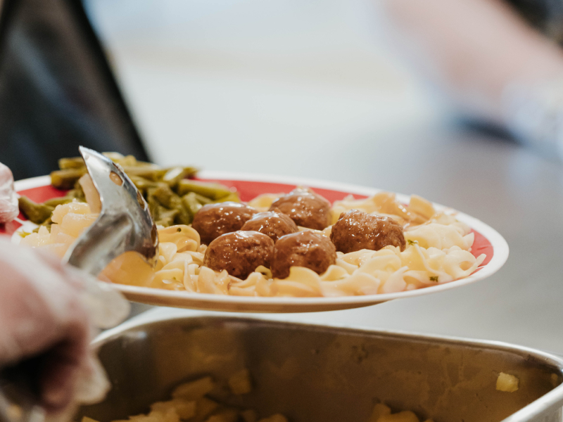 Close-up of a plate with Swedish meatballs, noodles, and green beans.