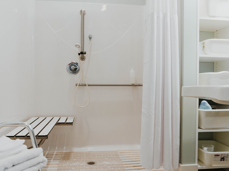 Handicap bathroom highlighting an accessible shower with grab bars and shower seat.